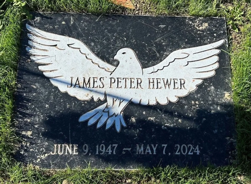 A black granite memorial marker with a dove before restoration