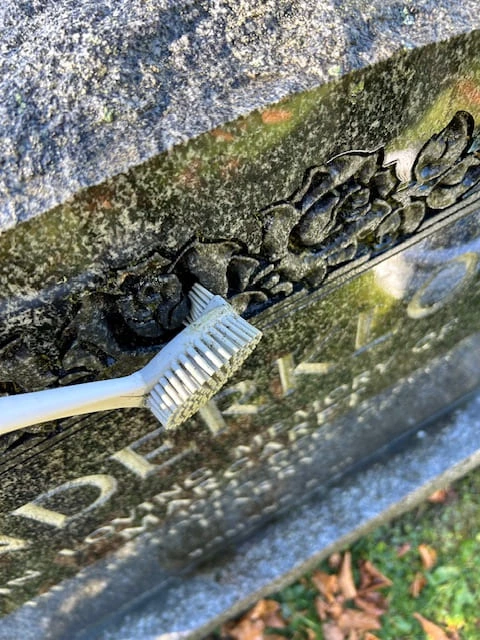 Cleaning crevice with a toothbrush in a granite monument